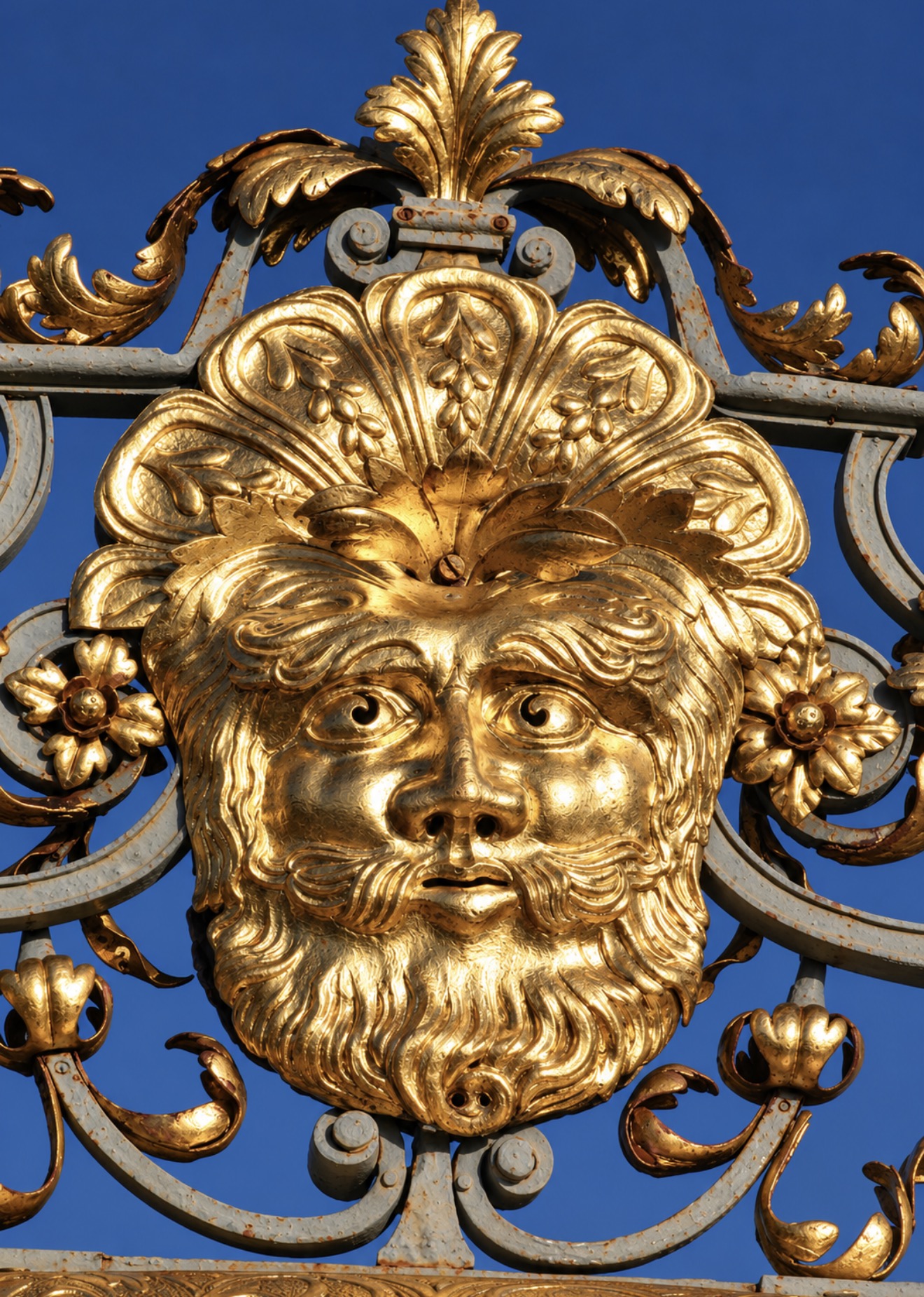 Close-up of a gilded bearded face framed by Baroque floral ornament