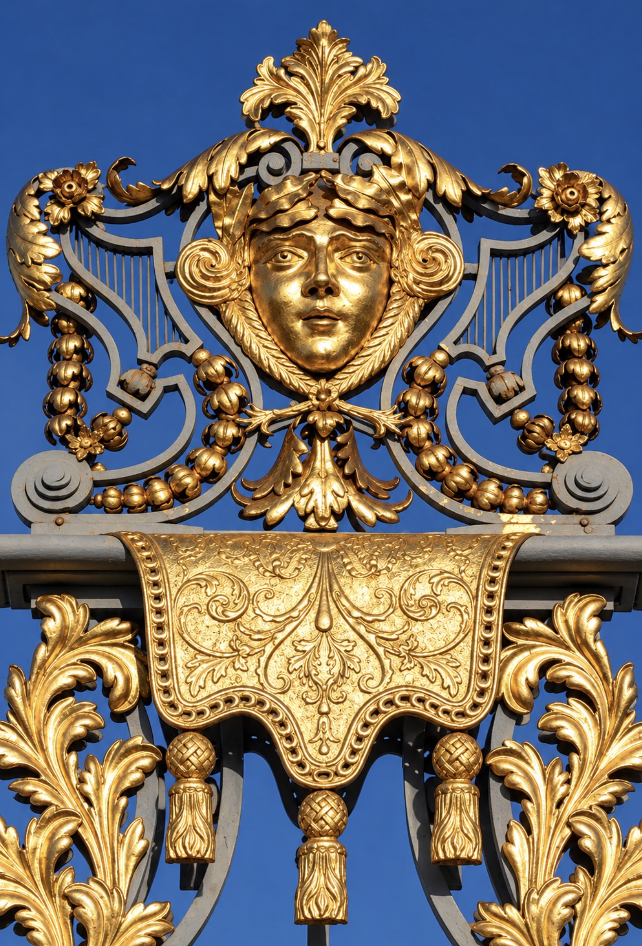 Close-up of a gilded female face above an ornamental draped panel