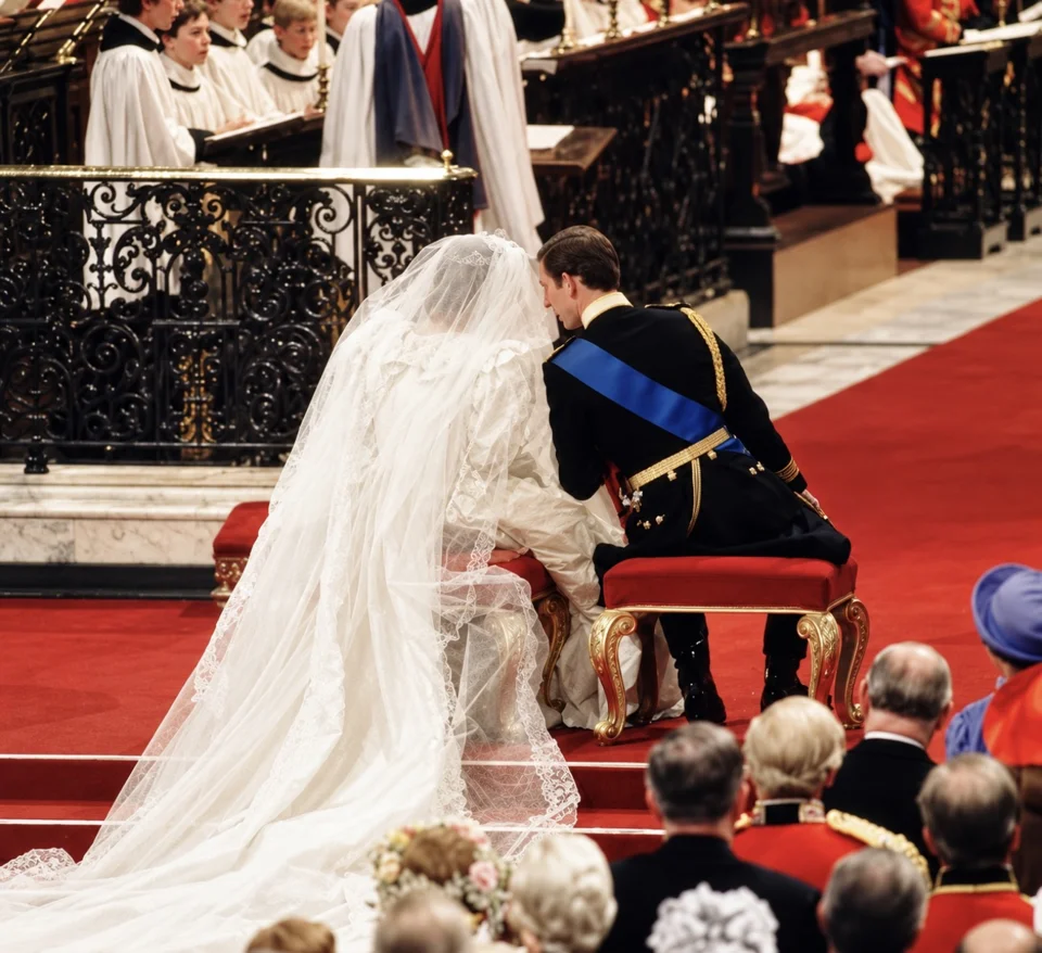 Charles and Diana seated during the service beside ornamental cathedral screens