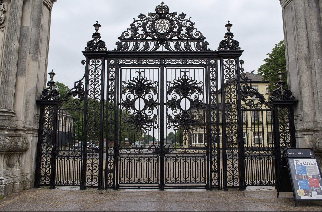 Ornamental black iron gates between stone piers identified by the owner as Petworth House